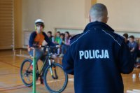 Zmagania uczniów na torze przeszkód pod czujnym okiem policjanta