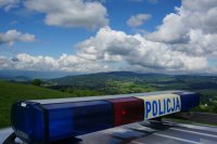 napis policja na dachu radiowozu, a w tle widok na góry