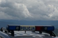 napis policja na dachu radiowozu, a w tle widok na zachmurzone niebo