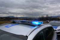 napis policja na dachu radiowozu, a w tle widok na góry i zachmurzone niebo