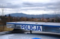 napis policja na dachu radiowozu, a w tle widok na góry i zachmurzone niebo