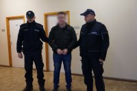 zatrzymany prowadzony przez dwóch umundurowanych policjantów. zatrzymany z kajdankami na rękach i na nogach