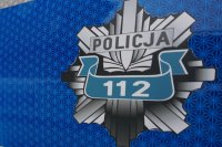 odznaka policyjna z numerem alarmowym 112 i napisem Policja