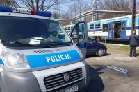 wóz policyjny i policjant na tle pociągu osobowego