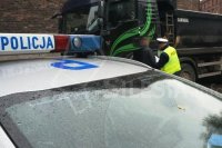 nap ierwszym tle sygnały radiowozu z napisem policja, w tle policjant kontroluje kierowcę ciężarówki