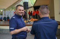 dzielnicowy sierż.szt. Boguław Bury po lewej uśmiecha się, po prawej odwrócony tyłem policjant