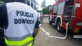 policjant z kamizelką Policja dowódca, po prawej wóz bojowy straży pożarnej