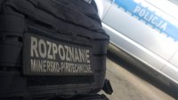 napis rozpoznanie minersko techniczne w tle radiowóz z napisem policja