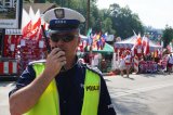 policjant rozmawia poprzez radiostację , w tle kibice