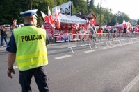 policjant pilnuje porządku na drodze na skocznię, w tle kibice