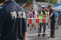 policjant pilnuje porządku na drodze na skocznię, w tle kibice