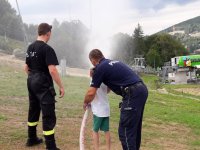 policjant i strażak z dzieckiem trzymającym wąż gaśniczy