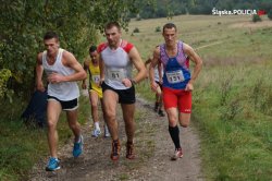 trzech biegnących mężczyzna w strojach sportowych z numerami startowymi na koszulkach