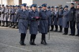 policjanci podczas marszu, środkowy niesie złożoną flagę Polski