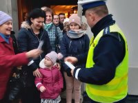 policjant rozdaje odblaski i mówi o bezpieczeństwie na drodze