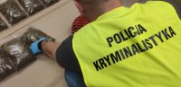 policjant w kamizelce technik kryminalistyki bierze ręką zapakowane narkotyki