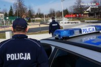 policjanci obserwują rtuch uliczny, stoją przy radiowozie