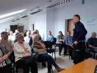 policjant rozmawia z seniorami i rozdaje odblaski