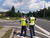 policjant po lewej i inspektor ITD po prawej stoją na drodze i kontrolują