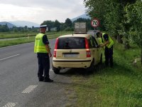 policjanci kontrolują samochód, jeden jest ustawiony z tyłu, drugi z prawej strony przez okno rozmawia z kierowcą