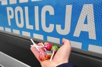 lizaki na dłoni, w tle samochód policji