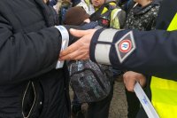 grafika- na zdjęciu po prawej stronie widać przedramię policjanta, który nakłada na przedramię kobiety opaskę odblaskową