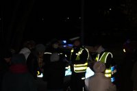 zdjęcie nocne- policjant wręcza elementy odblaskowe