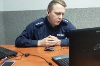 policjant przed laptopem, pomieszczenie biurowe