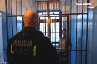 policjant obserwuje mężczyznę w celi za kratami