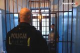 policjant obserwuje mężczyznę w celi za kratami