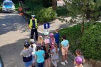grafika-policjant stoi obok znaku i rozmawia z dziećmi
