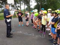 policjant rozmawia z dziećmi,stoi frontem do grupy dzieci
