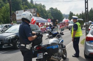 policjant przy motocyklu policyjnym, w tle droga, obok inny policjant