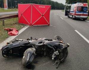 motocykl przewócony na jezdni, karetka pogotowia, czerwony parawan z napisem straż, dzień