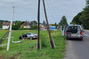 uszkodzony samochód w polu. Na drodze stoi policyjny samochód służbowy