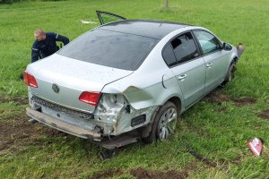 uszkodzony samochód w polu. Za samochodem widać policjanta