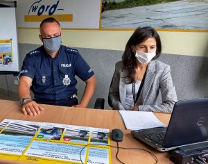 po lewej policjant, po prawej kobieta przed laptopem, siedzą, dzień , wnętrze pomieszczenia, patrzą na monitor