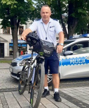 policjant trzyma rower, pozuje do zdjęcia