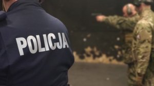 strzelnica zamknięta, sztuczne oświetlenie, policjanci oraz żołnierze celują do tarcz