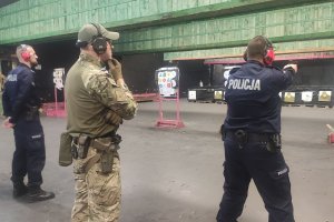 strzelnica zamknięta, sztuczne oświetlenie, policjanci oraz żołnierze celują do tarcz