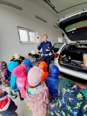 policjantka stoi przy radiowozie, dzieci się jej przyglądają