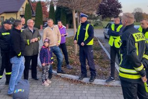 policjant oraz grupa ludzi pozuje do zdjęcia, dzień, zewnątrz budynku, parking