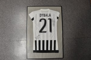 koszulka piłakrska z podpisami, koszulka biała z czarnymi pasami na dole, w górnej częsci napis Dybala