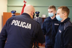 grafika-komendant gratuluje policjantowi ściskając jego dłoń