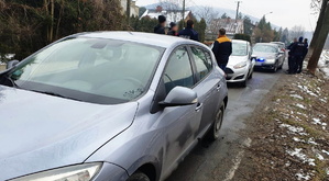 grafika, dzień, droga, samochody, wokół nich ludzie, w tle policjanci w mundurach