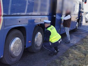 grafika, dzień, policjant sprawdza koła autobusu