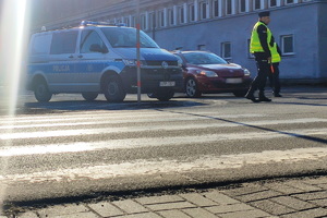 grafika-dzień, przejście dla pieszych, w tle radiowóz i policjanci