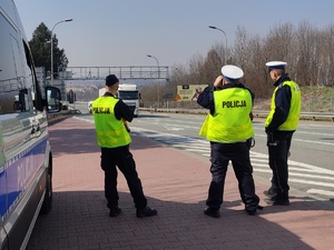 grafika, dzień, policjant patrzy przez lornetki i obserwuje pojazdy