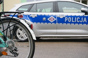 grafika-dzień, parking, rower, policyjny radiowóz w tle