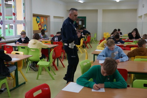 grafika- policjant , sala lekcyjna, uczniowie piszą test, dzień